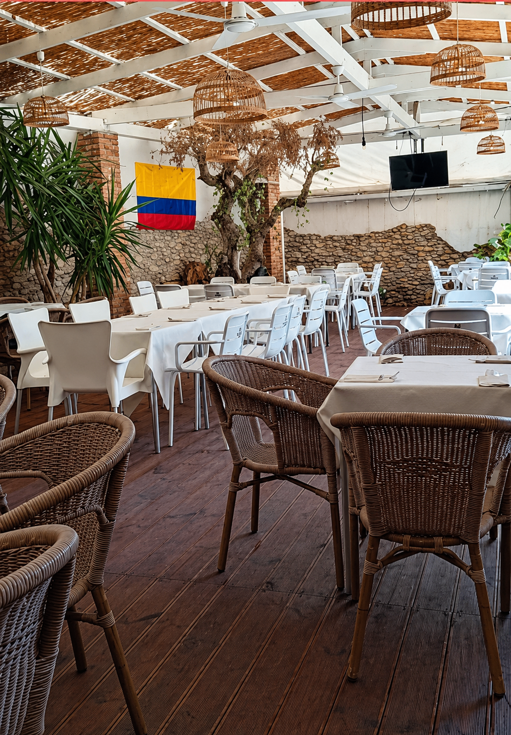 Sala principal con la bandera de Colombia y mesas vestidas de blanco